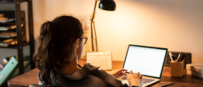 Mulher jovem, usando óculos de grau, trabalhando em home office.