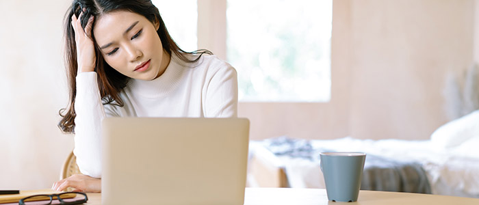 Atrasos no home office: Mulher preocupada em frente à notebook.