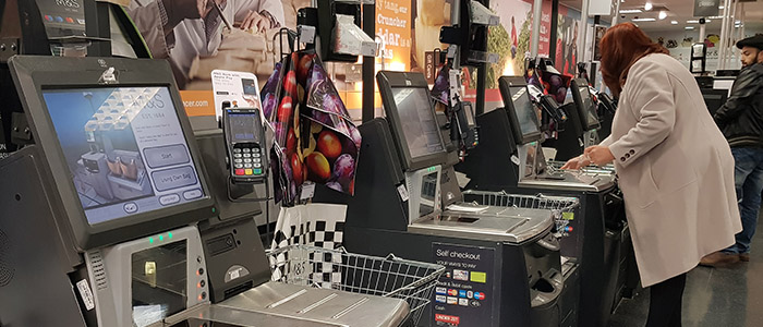 Automação comercial: Mulher usando self checkout em super mercado.