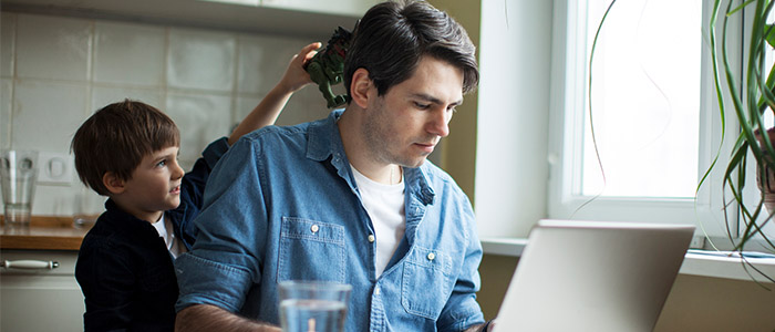 Homem tentando trabalhar em home office enquanto cuida de criança.