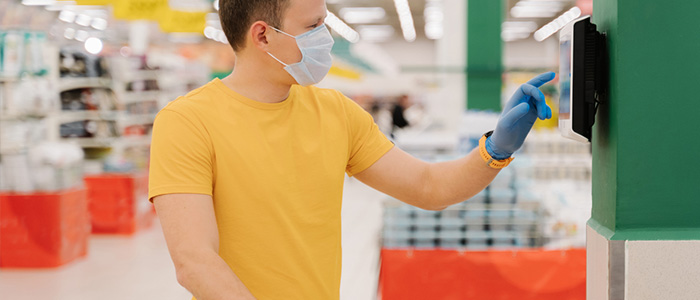 Homem de máscara e luvas no mercado usando o self checkout